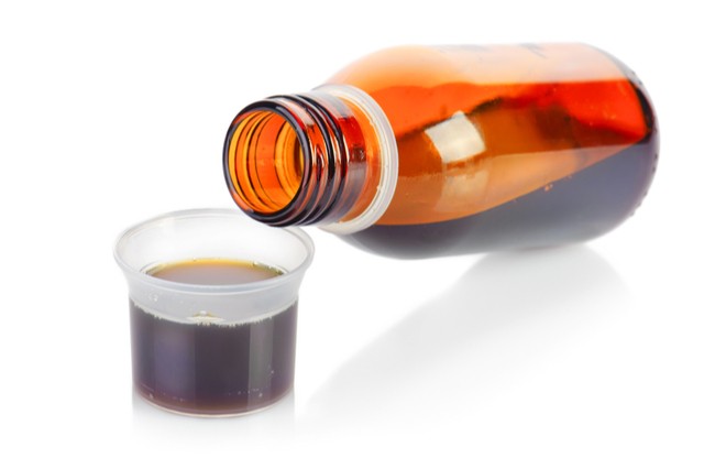 A bottle of cough syrup being poured into a cup, illustrates the dangers of lean addiction